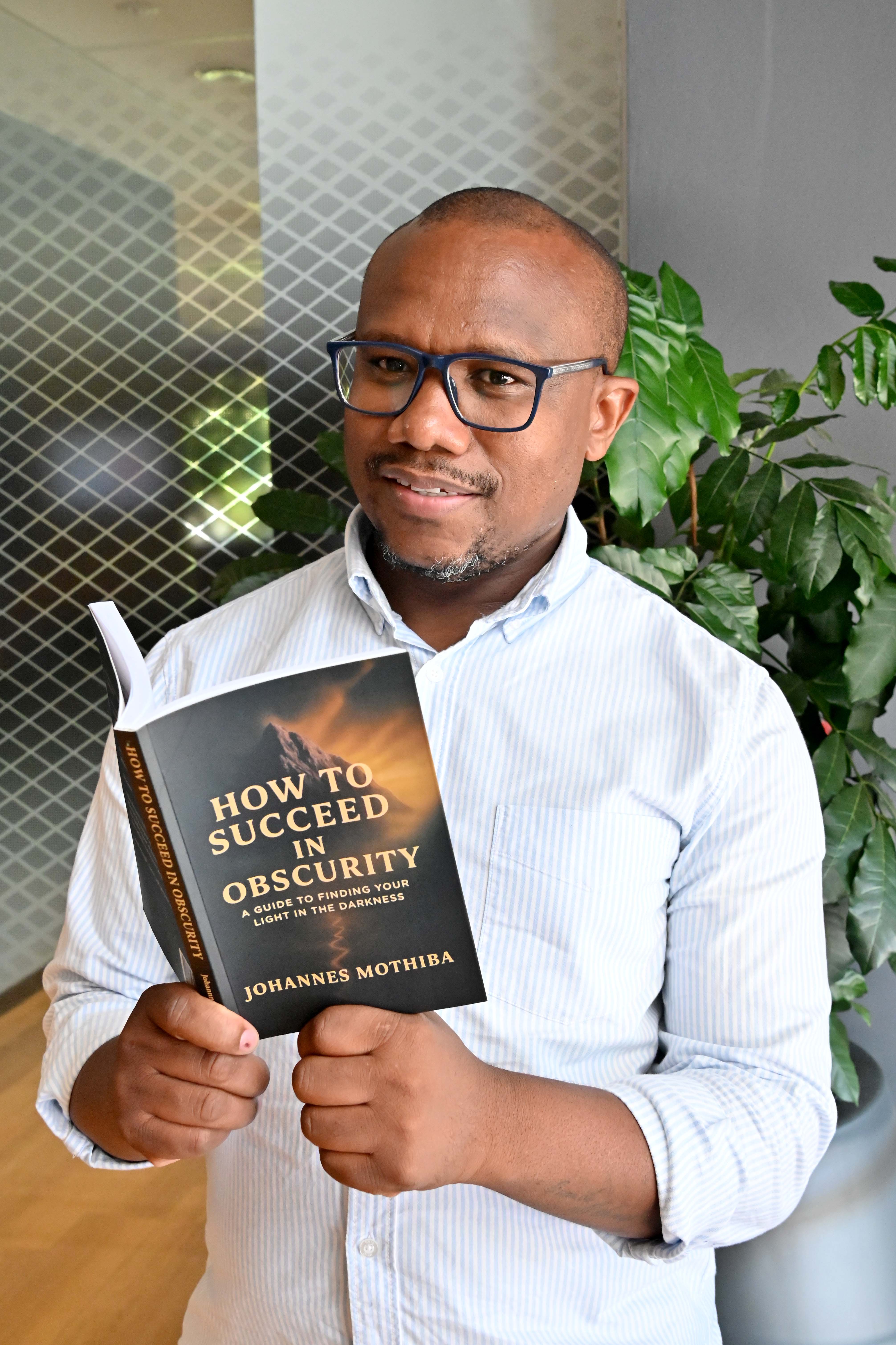 Johannes Mothiba holding his book open